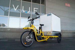 Vélo cargo de couleur jaune avec caisson arrière blanc.